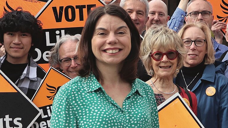 Sarah Olney MP with campaigners and Lib Dem diamonds behind her